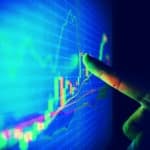 Closeup hand pointing finger on blue colour monitor to analyse stock market graph