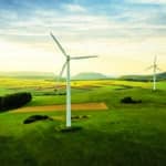 Alternative Energy Wind Turbine in Green Summer Landscape at Sunset